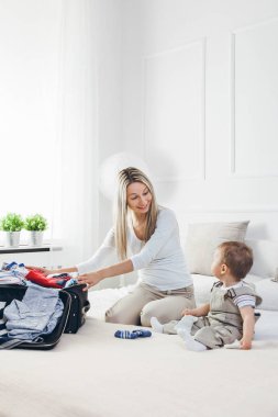 Çocuklarla seyahat. Mutlu anne çocuğunu giyim onların tatil için ambalaj ile
