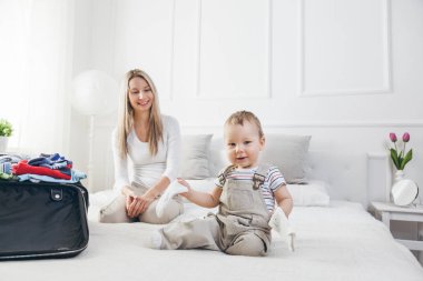 Çocuklarla seyahat. Mutlu anne çocuğunu giyim onların tatil için ambalaj ile