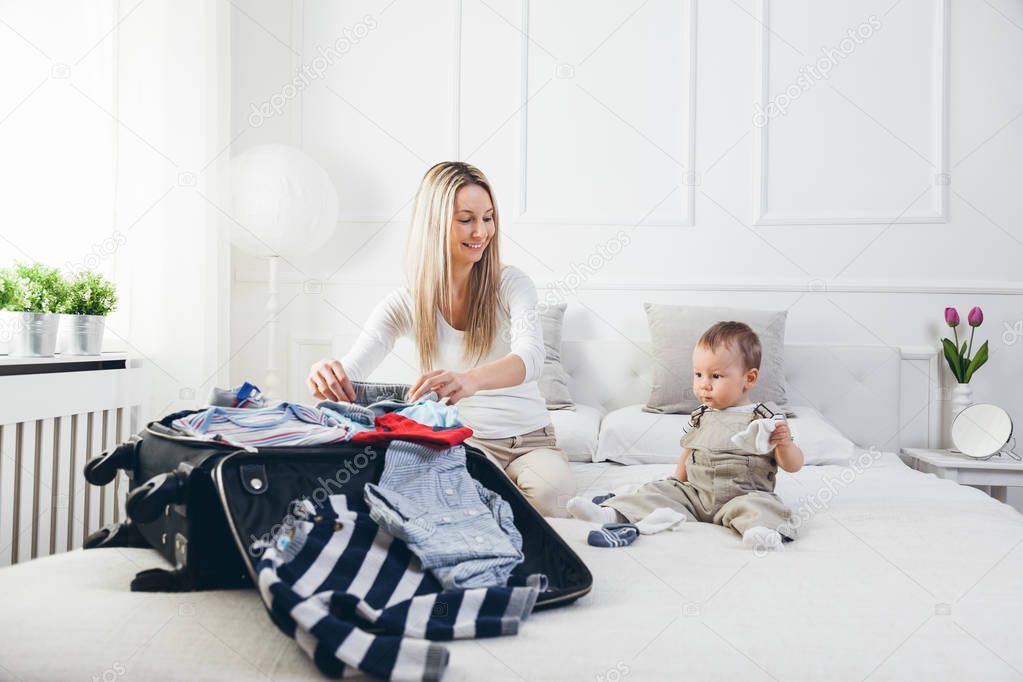 Travelling with kids. Happy mother with her child packing clothes for their holiday