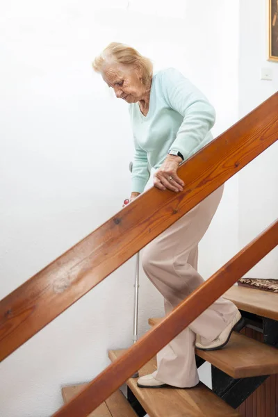 Mulher idosa em casa usando uma bengala para descer as escadas — Fotografia de Stock