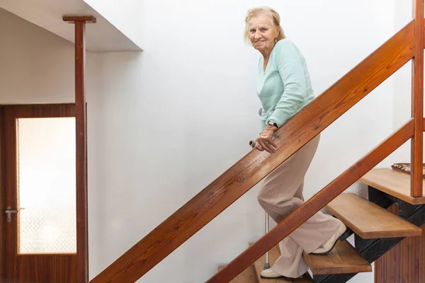 Ältere Frau zu Hause mit einem Stock die Treppe hinunter — Stockfoto