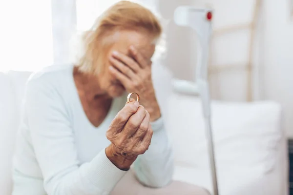 Donna anziana spezzata di cuore che tiene una fede nuziale — Foto Stock
