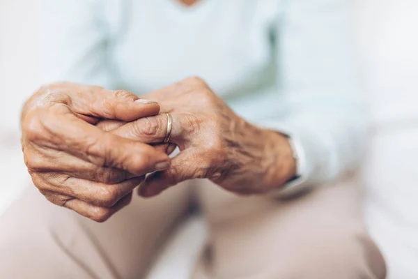 Donna anziana spezzata di cuore che tiene una fede nuziale — Foto Stock