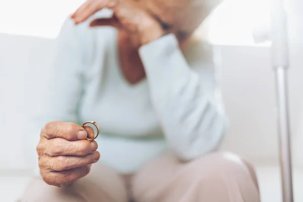 Donna anziana spezzata di cuore che tiene una fede nuziale — Foto Stock