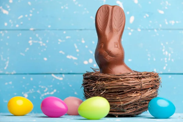 Lapin de Pâques chocolat, oeufs et bonbons sur fond rustique — Photo