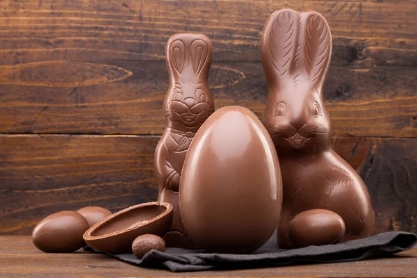 Čokoládové Velikonoční zajíček, vejce a sladkosti na rustikální pozadí — Stock fotografie