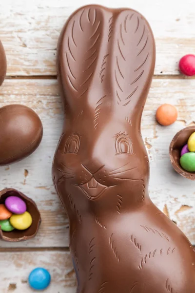 Čokoládové Velikonoční zajíček, vejce a sladkosti na rustikální pozadí — Stock fotografie