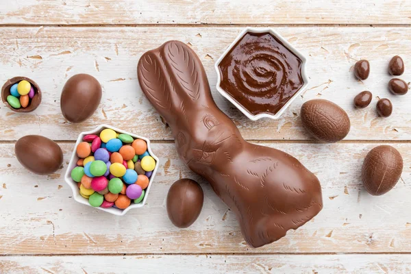 Chocolate Easter bunny, eggs and sweets on rustic background — Stock Photo, Image