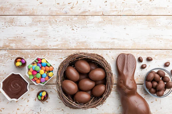 Coelho de Páscoa de chocolate, ovos e doces em fundo rústico — Fotografia de Stock