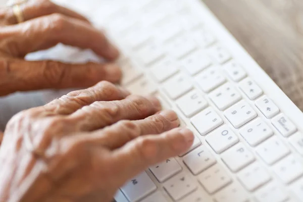 Oudere vrouw typen op een toetsenbord — Stockfoto