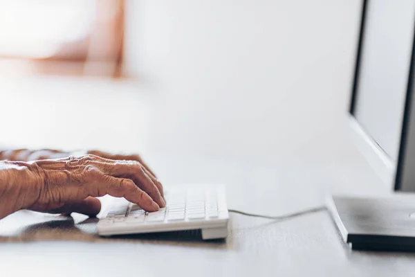 Elderly woman typing on a keyboard — Stock Photo, Image
