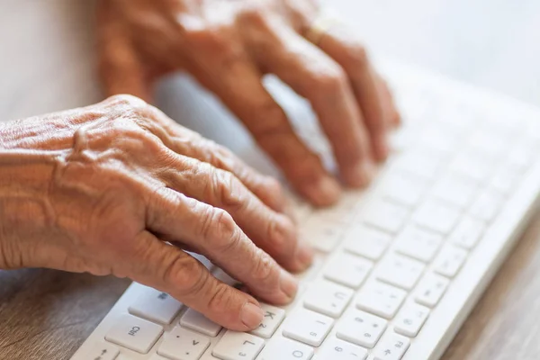 Mujer mayor escribiendo en un teclado — Foto de Stock