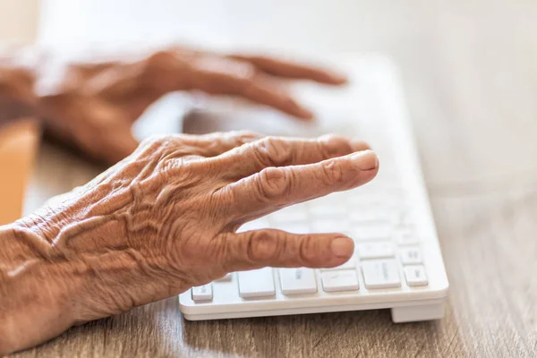 Пожилая женщина печатает на клавиатуре — стоковое фото