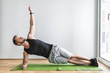 Yakışıklı genç adam evde akıllı bir saatle çalışıyor.