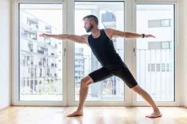 Genç yakışıklı adam evde yoga yapıyor.