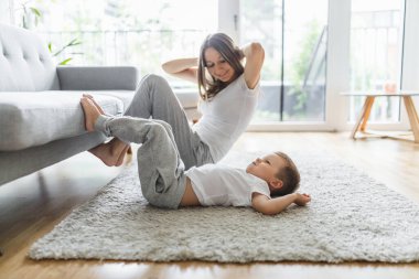 Anne ve küçük oğlu oturma odasında çalışıyor.