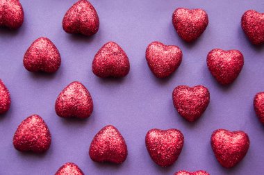 mor arka planda kırmızı parlak kalpler