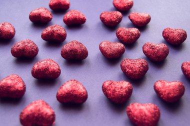 mor arka planda kırmızı parlak kalpler