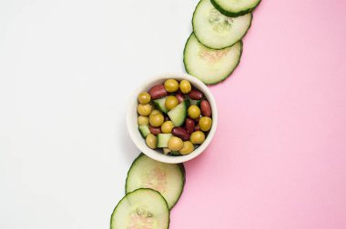 beyaz pembe arka plan üzerinde dilimlenmiş taze salatalık ve salata