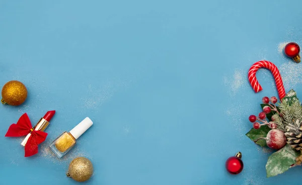 Yeni yılın geçmişi. Altın bir kutuda kırmızı ruj, karamel kamış, Noel ağacı ve mavi arka planda Noel topları. Metin için yer aç. Resmin altındaki bileşim.