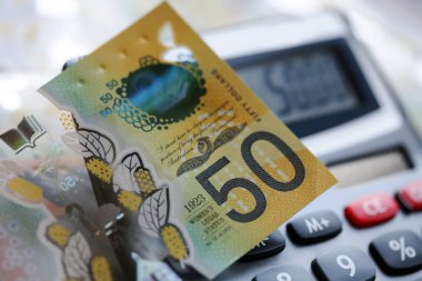 Bir hesap makinesi üzerinde Avustralya elli dolarlık banknot. Yeni 2019 sayı tasarısı sahteciliği caydırmak için tasarlanmıştır, not polimer ve berrak bir holografik şerit ile suya dayanıklıdır.