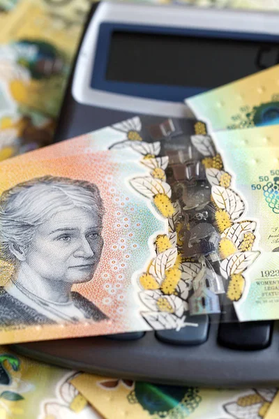 Australian fifty dollar banknote over a calculator. The new 2019 issue bill is designed to deter counterfeiting, the note is polymer and water resistant with a clear holographic strip in a vertical format.