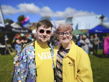 Swansea, İngiltere: 04 Mayıs 2019: Birleşik Krallık'taki Gay Pride Parade'in katılımcıları ve destekçileri. İki genç yetişkin bir Gay Pride Parade sırasında kameraya gülümseme - toplumda çeşitlilik ve alternatif yaşam tarzları desteklemek.