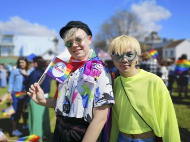 Swansea, İngiltere: 04 Mayıs 2019: Gay Pride Parade katılımcıları ve destekçileri. Renkli giysiler içinde iki genç yetişkin geçit töreni sırasında gülümseme - toplumda çeşitlilik ve alternatif yaşam tarzları desteklemek için.