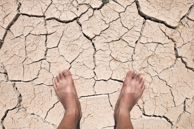Crack dry ground on foot, drought concept. clipart