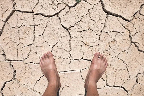 Crack dry ground on foot, drought concept.