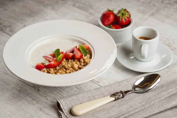 新鮮なイチゴと緑のミントとオートミールのクローズ アップ写真はコーヒーのカップの灰色の木製テーブルの上葉白い皿にミルクで — ストック写真