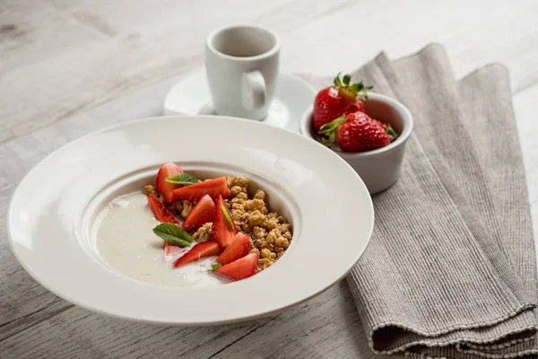 新鮮なイチゴとミント グリーンと健康的なオートミールのクローズ アップ写真が白い皿にミルクで灰色の木製テーブルの上葉します — ストック写真
