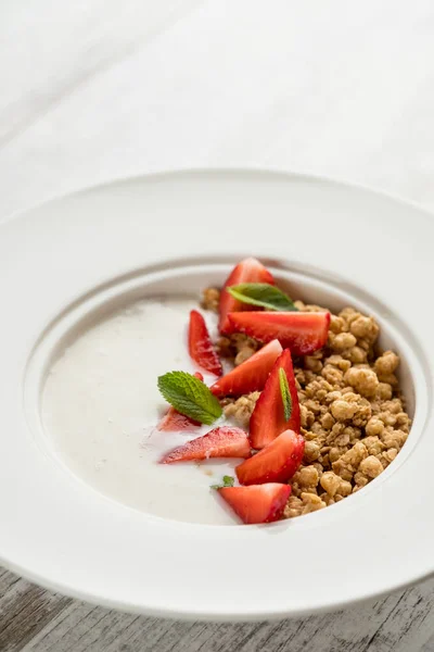 健康的な朝食のクローズ アップ写真 白プレート グレー木製テーブルの上に 新鮮なイチゴと甘いオートミール — ストック写真