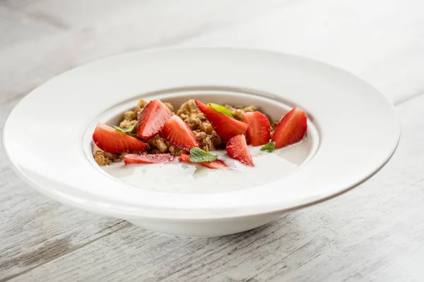 健康的な朝食のクローズ アップ写真 白プレート グレー木製テーブルの上に 新鮮なイチゴと甘いオートミール — ストック写真