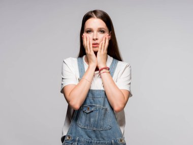 Onun yüzünü dokunaklı gri arka plan üzerinde duran sürpriz genç kadın