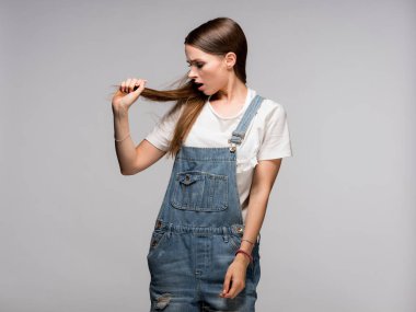 Gri arka plan üzerinde onu uzun saçlı ayakta tutan üzgün esmer kadın