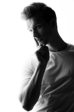 Genç adam izole üzerinde beyaz arka plan ayakta parmak sessizlik işaretiyle gösterilen