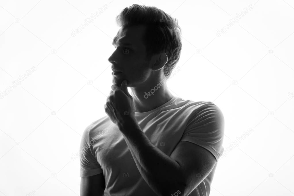 young thoughtful man touching his chin standing on white background