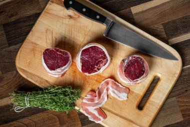 Zanaat sığır eti biftek mermer eti fileto mignon pastırma içinde yemek pişirmek için seçili. Ahşap arka plan.