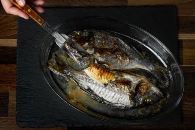 Ahşap masa üzerinde cam tavada pişmiş balık pişirme Şef