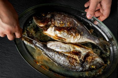 Ahşap masa üzerinde cam tavada pişmiş balık pişirme Şef