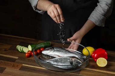 Deniz yemek balık ahşap masa üzerinde narenciye ve sebze malzemelerle Şef