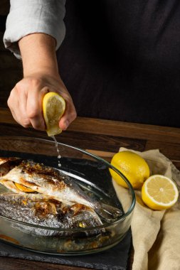 Ahşap masa üzerinde cam tavada pişmiş balık pişirme Şef