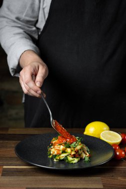 Şef yemek peynir ve domates sosu, siyah arka plan mutfak merdivenlerinde ile kabak İtalyan yemek pişirme.