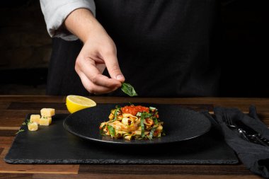 Şef yemek peynir ve domates sosu, siyah arka plan mutfak merdivenlerinde ile kabak İtalyan yemek pişirme.