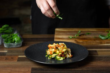 Şef yemek peynir ve domates sosu, siyah arka plan mutfak merdivenlerinde ile kabak İtalyan yemek pişirme.