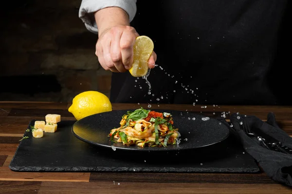 Chef cooking zucchini Italian dish cooking with cheese and tomato sauce, steps on black background kitchen.