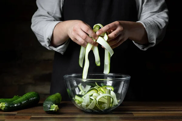 Chef cooking fresh zucchini slices in glass bowl for cooking vegetables diet salad. Healthy food concept