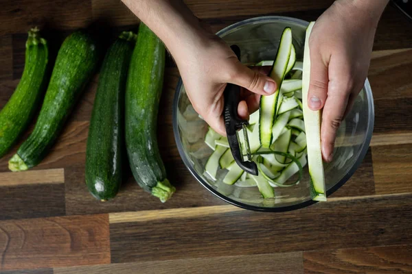 Chef cooking fresh zucchini slices in glass bowl for cooking vegetables diet salad. Healthy food concept