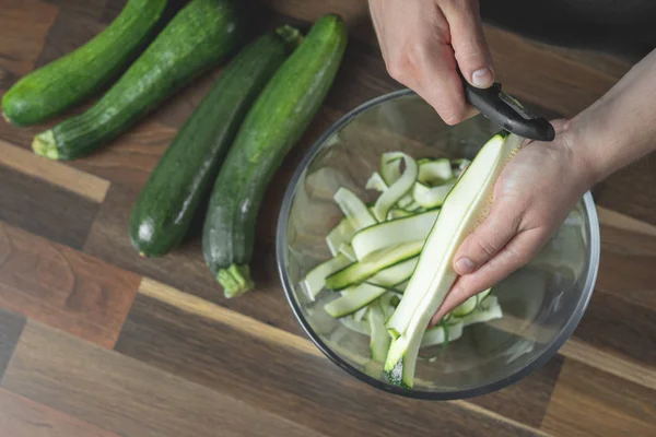 Chef cooking fresh zucchini slices in glass bowl for cooking vegetables diet salad. Healthy food concept